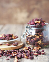 Dried hawthorn in a glass jar on a wooden ancient background.Home harvesting of dried fruits.