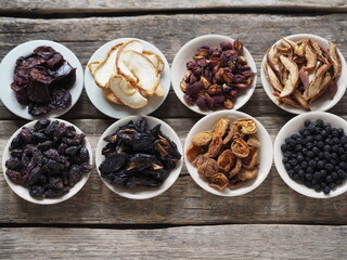 Bowls with various dried fruits on a wooden ancient background. Home preparation of dried fruits.