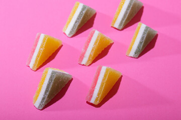 Set of colorful triangular jelly candy lined up on pink background.