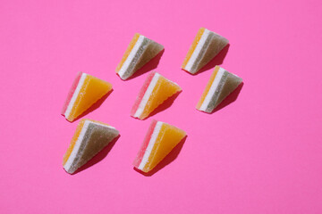 Set of colorful triangular jelly candy lined up on pink background.