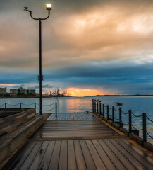 Fototapeta premium pier at sunset sunrise cloudy day clouds sea pier birds seagulls wooden floor wet rain 
