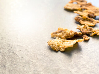 A group of corn flakes on a gray floor