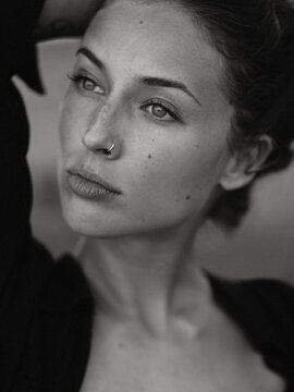 Close up black and white portrait of a young beautiful woman with nose piercing