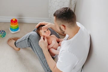 Fathers Day holiday. Proud Caucasian father playing with newborn baby girl. Parent holding rocking...