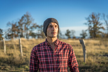 portrait of a 30 year old man in a red checkered shirt and gray wool hat