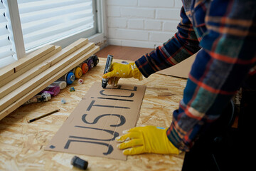 a man draws posters with a black marker that say justice and black lives matter