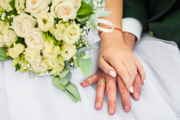 Bride and groom holding hands . Wedding rings and bride's bouquet detail. 