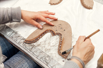 A worker painting glue onto a shoe piece in a shoe factory