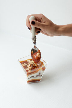 a woman's hand breaks off a piece of dessert with caramel, nuts, chocolate and nougat