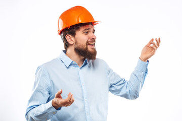 A man in an orange helmet shirt construction industry worked light background