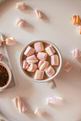 Ceramic cup of hot chocolate or cocoa with marshmallow on white table. Decoration garlands of lights. Flat lay, healthy food concept