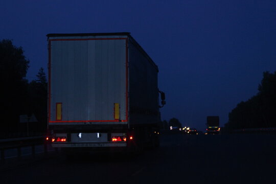 Semi Trailer Truck Move On Dry Asphalted Night Road In Dark, Back View - Intrenational Transportation Logistics