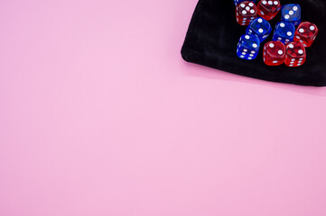 Top view of red and blue dice on a dice bag isolated on light pink background