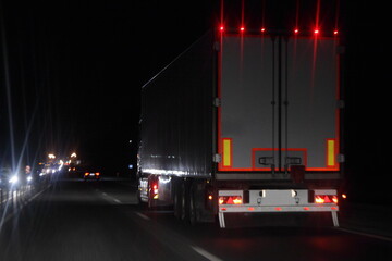 Semi trailer truck with lighting reflection stripe on rear board move on dry asphalted night road in dark, back view - intrenational transportation logistics © Ilya