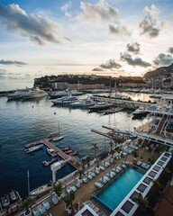 A luxury yacht harbor in Monte Carlo at sunset with blue water and a pool in the foreground