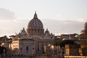 Fototapeta na wymiar Saint Peter's Basilica in the Vatican Rome at sunset with birds flying