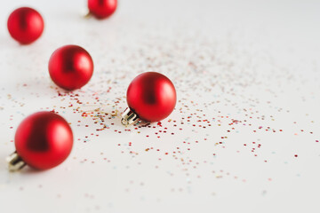 Background with small red Christmas balls and colorful glitters on white background