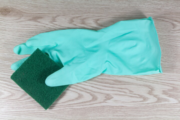 Scrub pad and rubber glove on wooden background