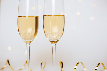 Two glasses of champagne with lights and ribbons on a white background holiday