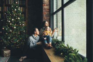 Happy family at home in cozy living room with a decorated festive Christmas tree