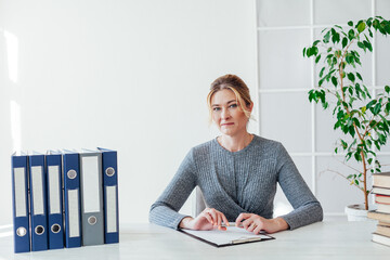 woman in business suit at work in office at a table with books and documents