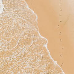 A path of footprints in the sand on a beach by the waves of the Pacific Ocean