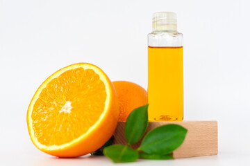 Orange oil for the body. Orange on a wooden pedestal on a white background. Organic SPA cosmetics with herbal ingredients.