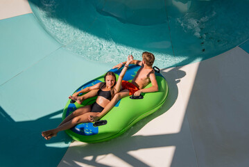 Girl and boy in water Park. Fun on the water. Teen girl and boy having fun in the water slider ....