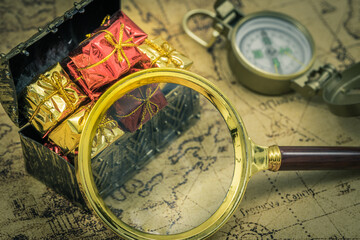 The treasure hunt. A magnifying glass and a compass next to a chest full of treasures. Old map,...