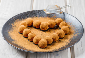 chocolate truffles or energy protein balls made with dry dates, walnuts, raisins, covered by cocoa powder