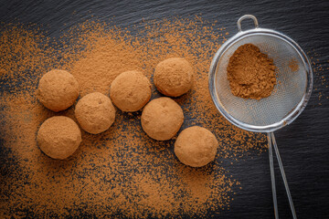 chocolate truffles or energy protein balls made with dry dates, walnuts, raisins, covered by cocoa powder