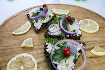 sandwiches with herring lemon cheese and onions on a wooden Board