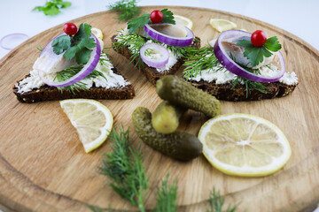 sandwiches with herring lemon cheese and onions on a wooden Board