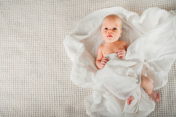 Newborn baby in a white diaper close up. Baby swaddling in muslin diaper and copy space.