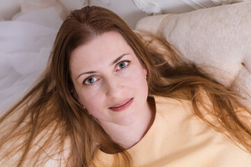 Attractive midle aged woman laying on sofa and looking up into the camera