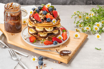 Pancakes with chocolate paste and hazelnuts, banana, strawberry and blueberry