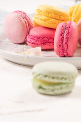 Colorful french macaroon cakes. Macaroons with jasmine flowers on white table background. Selective focus