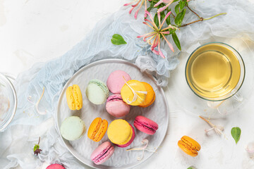 Colorful french macaroon cakes. Macaroons with jasmine flowers and tea on white table background. Selective focus