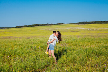 Woman holds baby in her arms in nature in a field with flowers