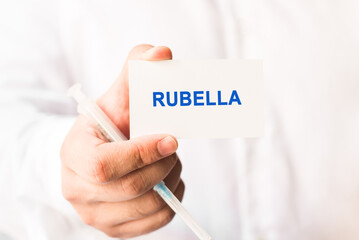 Word rubella on a white background with a syringe in hand. Medicine concept