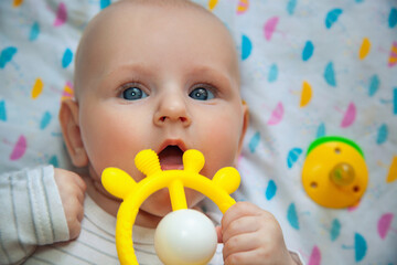 Cute little boy using yellow teether toy.