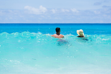 Lover couple enjoy turquoise color waves of indian ocean, in Seychelles