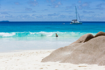 Young boy enjoy the beach at summer vacation in turquoise color waves of indian ocean, in Seychelles