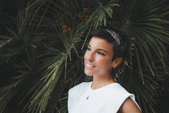 Dreamy woman with a beautiful smile looking away with plants in the background