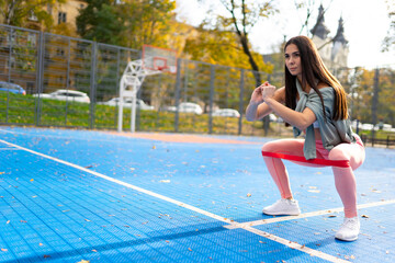 Obraz premium Athletic woman doing squats with resistance bands