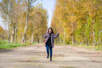 Fototapeta premium outdoors lifestyle portrait of young happy and pretty Asian Chinese woman jumping carefree and cheerful at beautiful city park in vibrant yellow and orange Autumn tree leaves