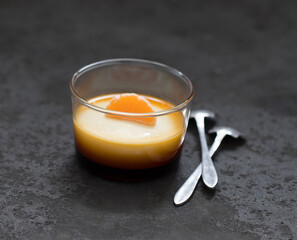 Cream caramel pudding with tangerine in a glass Cup on a dark background