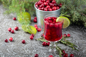 Glass of cranberry drink with berries, lime, and rosemary.