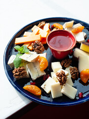 cheese plate with various types of cheese, as well as honey, nuts and dried apricots