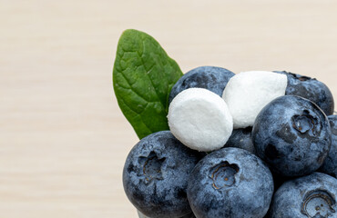 Huge juicy fresh blueberries with marshmallow and green leaf in the small glass. close-up